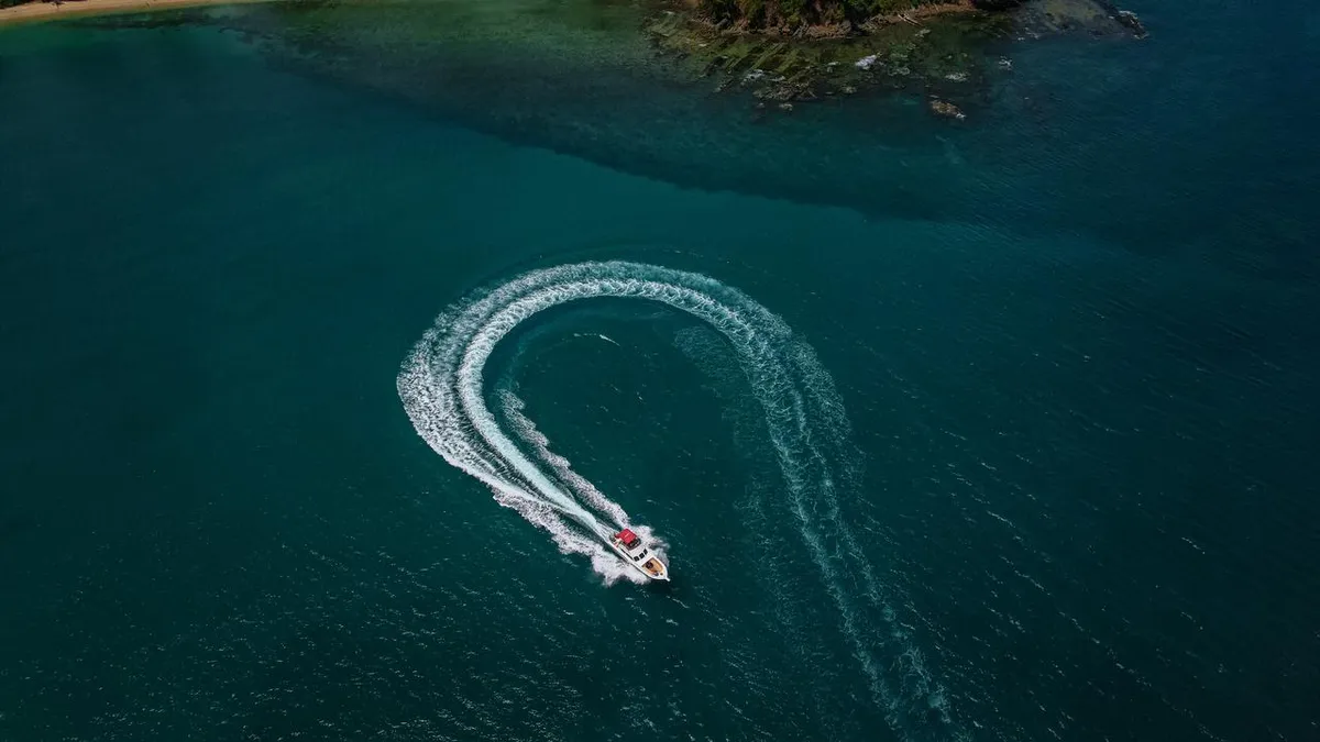 Speedboat carving through turquoise water near the Elephant Beach reef, Havelock